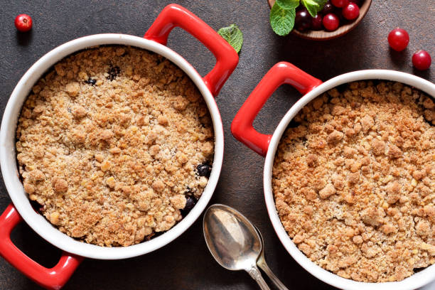 crumble con arándanos y otras bayas, nueces en la mesa de la cocina. vista desde arriba. - apple portion red freshness fotografías e imágenes de stock