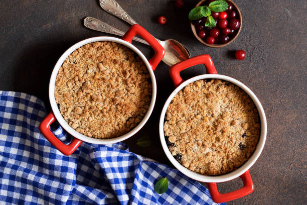 crumble con arándanos y otras bayas, nueces en la mesa de la cocina. vista desde arriba. - apple portion red freshness fotografías e imágenes de stock