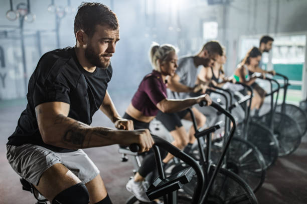 istock Determined man making an effort while exercising on stationary bike on training class. 1147310159