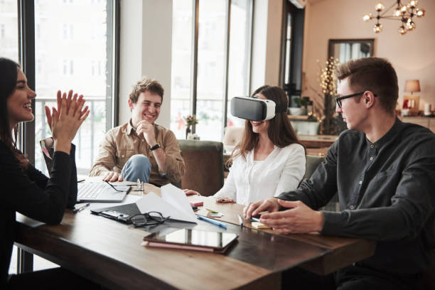 istock First time experience with virtual reality glasses. Having fun in the office room. Friendly coworkers playing around at their break time 1147310998