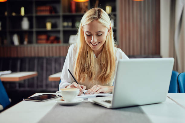 istock Businesswoman taking notes in notebook while sitting in cafe. 1147312637