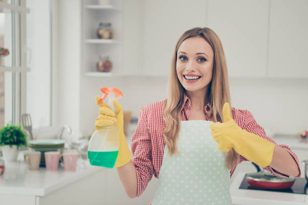 Close up photo beautiful nice duties she her lady stand shiny white bright kitchen house finished work hold detergent advising use user buy buyer wear casual jeans denim shirt apron flat indoors. cerca de la foto hermosas funciones bonitas ella su dama de pie brillante casa de cocina brillante blanco terminado trabajo de retención de detergente de uso de usuario de compra del comprador usar jeans casual camisa de mezclilla delantal interior