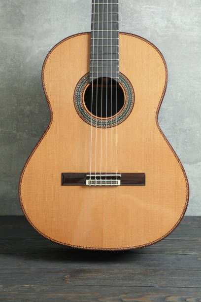 istock Beautiful six - string classic guitar on wooden table against grey background 1147314415