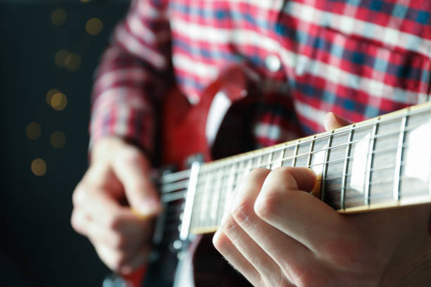 istock Man playing on electric guitar against dark background, closeup 1147314513