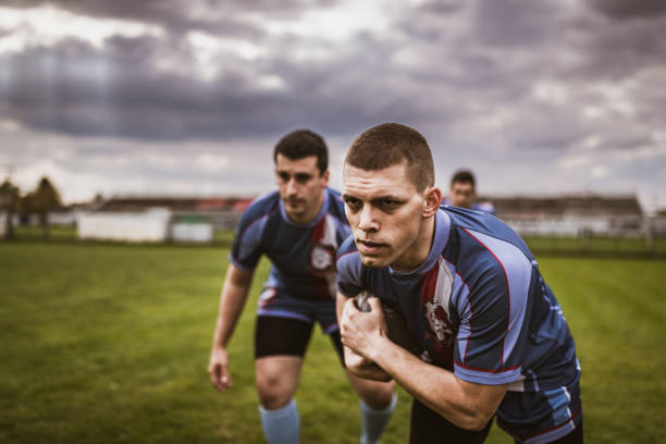 istock Determined rugby players running with ball on a playing field. 1147315081