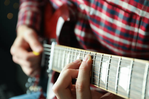 istock Man playing on electric guitar against dark background, closeup 1147315181