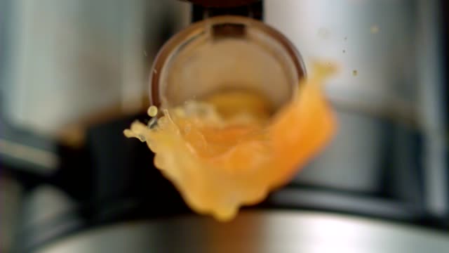 Orange juice pouring out of juicer. Super Slow motion