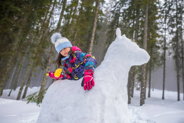 Girl making horse with snow outdoors.