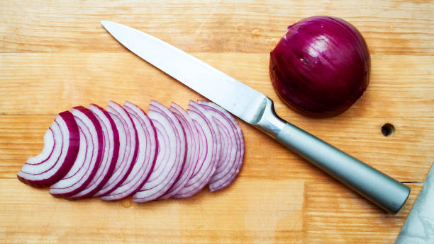 red onion and knife on a wooden board