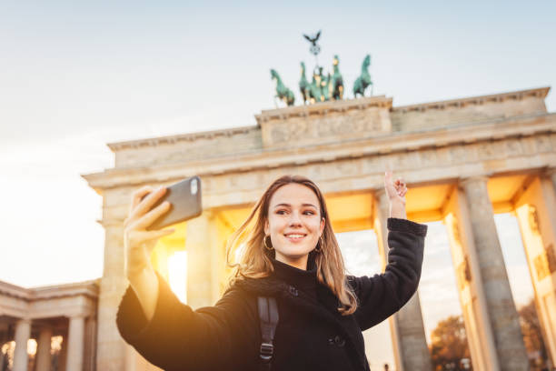 junge frau bei selfie am brandeburger tor in berlin - brandenburger tor stock-fotos und bilder