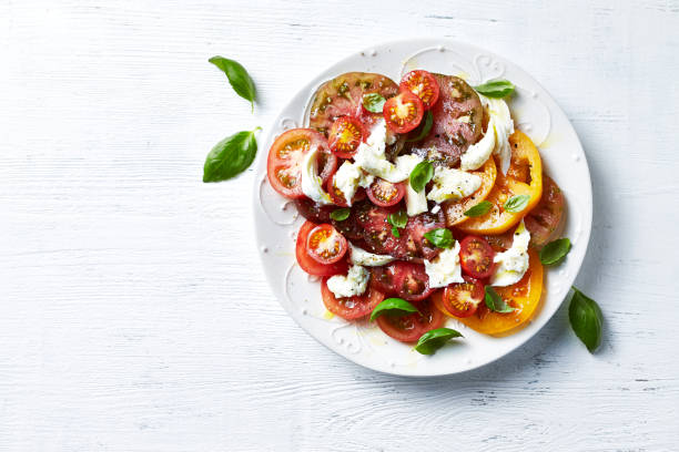 mixed tomato salad with mozzarella cheese and basil leaves. mediterranean cuisine - caprese salad fotos imagens e fotografias de stock