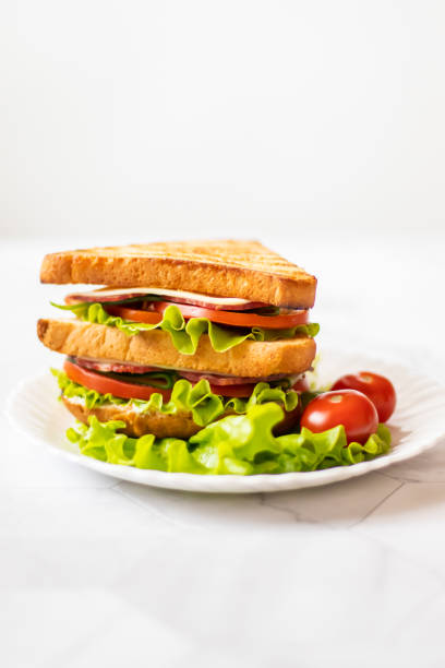 istock Sandwich with cheese, tomato, cucumber, sausage and salad on a light background. Vertical orientation 1147321633