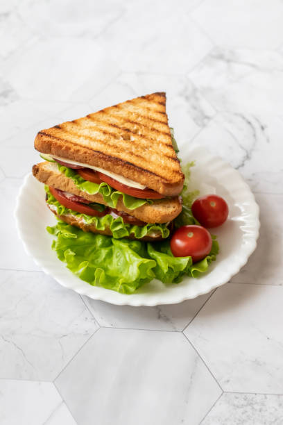 istock Sandwich with cheese, tomato, cucumber, sausage and salad on a light background. Vertical orientation 1147321890