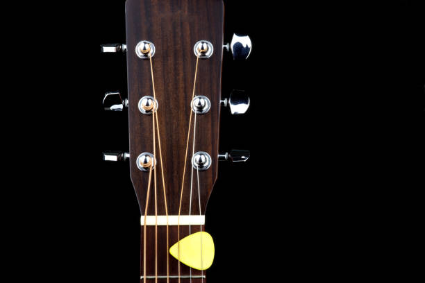 istock Acoustic Guitar Peg Head with Plectrum on a Black Background 1147324354