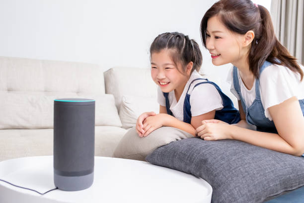 Smart AI speaker concept Smart AI speaker concept - Mom and daughter talk to voice assistant at home and feel happy smart home family stock pictures, royalty-free photos & images