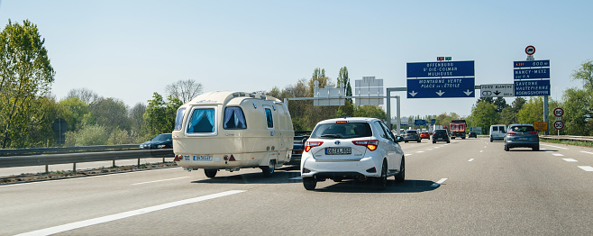 Strasbourg, France - Apr 19, 2019: Congested traffic on French highway perspective view at the long autoroute with electric Toyota Yaris and convertible Mercedes-Benz with vintage retro RV trailer camp