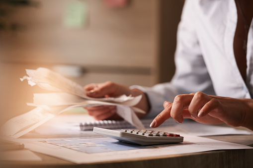 Close up de empresaria usando calculadora mientras pasa por las facturas financieras. photo