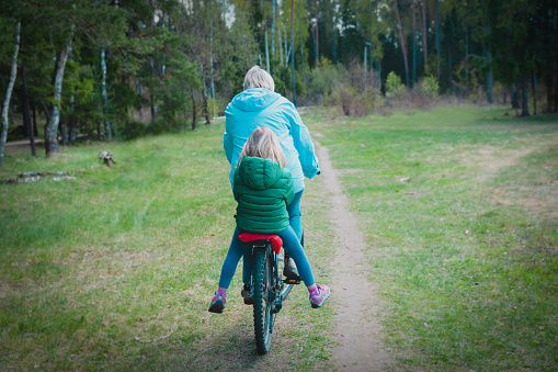 active senior grandmother with granddaughter on bike ride in nature