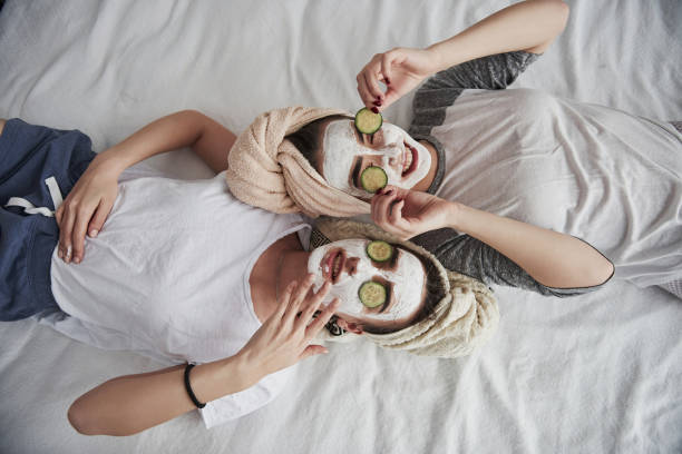 Taking off these things. Lying on the white bed. Top view. Conception of skin care by using white mask and cucumbers on the face Taking off these things. Lying on the white bed. Top view. Conception of skin care by using white mask and cucumbers on the face. facial mask beauty product stock pictures, royalty-free photos & images