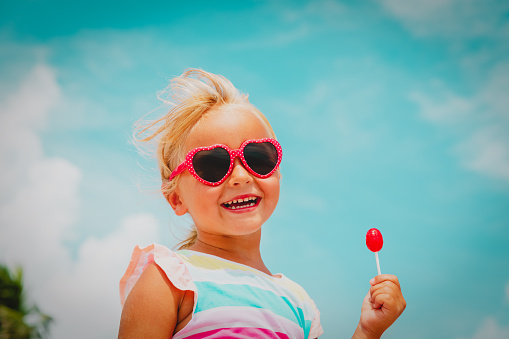 happy cute little girl with lollipop on summer beach vacation