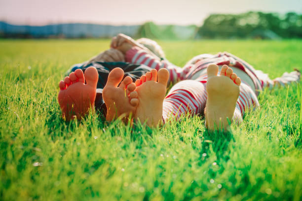 happy children feet on green grass, summer relax stock photo