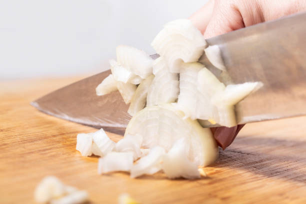 istock cook cuts onion on a wooden board 1147337469