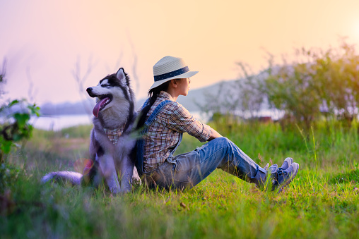 woman girl enjoy sitting with a puppy dog at foredst of lake river with sunset sweet time, friendship and relationship together in comfortable time