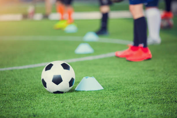 istock football between marker cones on green artificial turf with blurry soccer team training 1147339907