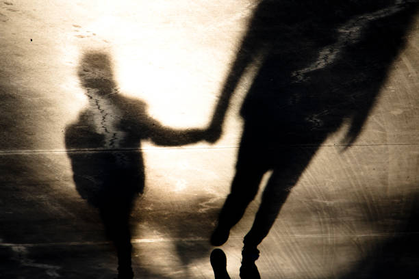 siluetas de sombra de padre e hijo caminando de la mano - inmigrante fotografías e imágenes de stock