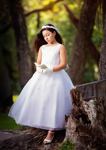 Cute girl in fairy dress and golden crown holding magic wand on pink background. Little princess