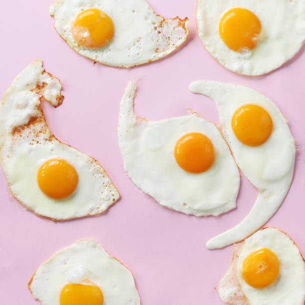 istock Fried eggs or scrambled eggs pattern on pink background. Creative food concept. Top view. Square crop 1147349845