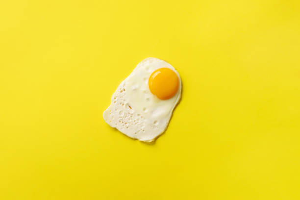 istock One fried egg on yellow paper background. Creative food concept in minimal style. Top view 1147349915
