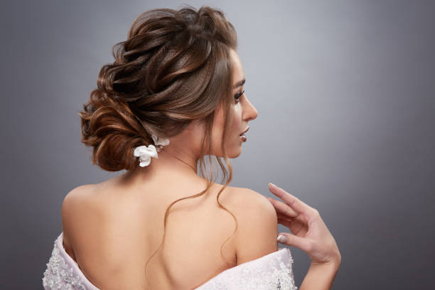 bride with pretty hairstyle touching her shoulder and looking sideways stock photo