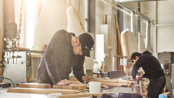 projets personnalisés avec une valeur artistique, orientée vers le design. portrait de travailleur caucasien retenant une brosse, appliquant la peinture de vernis sur un meuble en bois - menuisier photos et images de collection