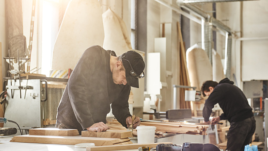 Woodwork and furniture making concept. Carpenter in the workshop varnishes furniture cabinet. Horizontal shot