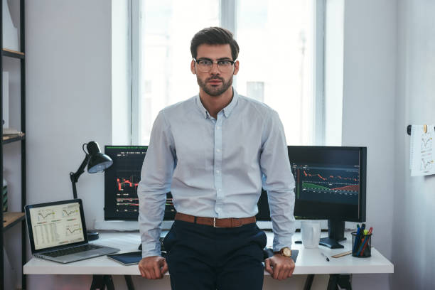 istock Modern trader. Successful young businessman in formal clothes and eyeglasses looking at camera while standing in the office 1147352007