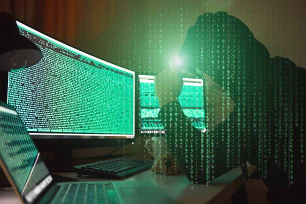 istock Cyber crime. Side view of young hacker in black hoodie using multiple computers and his smartphone for stealing data while sitting in dark room. 1147352300