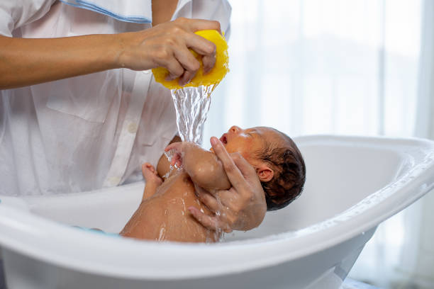 화이트 욕조에 작은 신생아 아기 목욕 흰색 셔츠 어머니 사용 노란색 스폰지 - bathtub women bathroom asian ethnicity 뉴스 사진 이미지