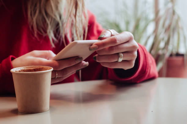 istock Smiling woman in cafe using mobile phone and texting in social networks, sitting alone 1147358437