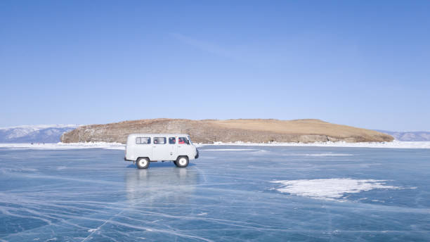 The old car moves on the ice of lake Baikal during the tour. A winter journey in Russia stock photo