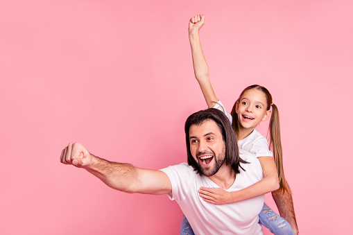 Close up photo beautiful she her little lady he him his daddy dad hold little princess piggyback hands arms ready fly save people wear casual white t-shirts denim jeans isolated pink bright background.