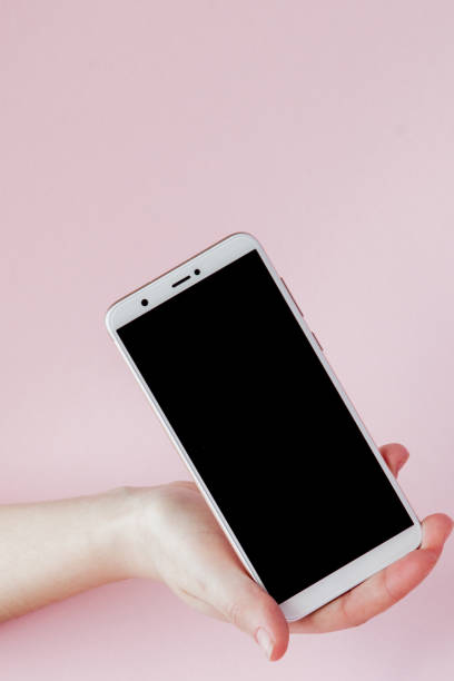 istock Modern mobile phone in a woman's hand on pink background 1147364755