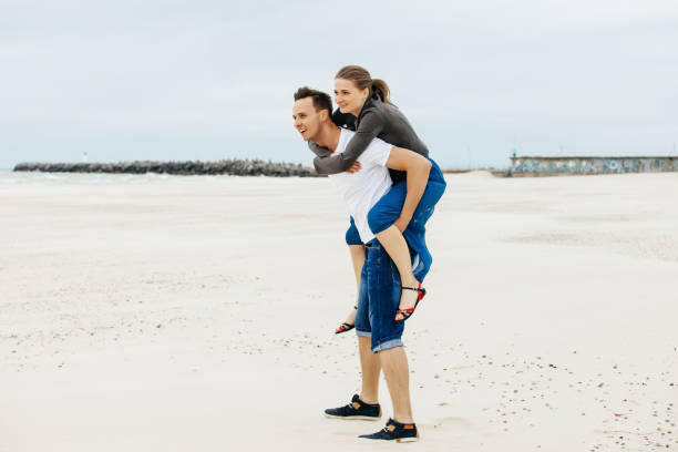 istock A guy carrying a girl on his back at the beach. 1147367298