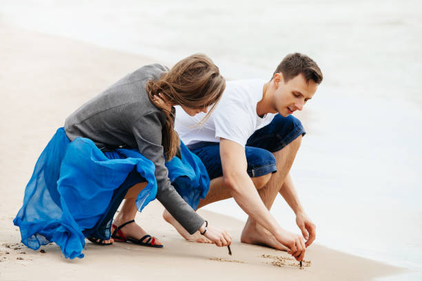 istock Young couple on the beach drawing in sand. 1147367340