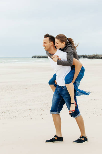 istock A guy carrying a girl on his back at the beach. 1147367359