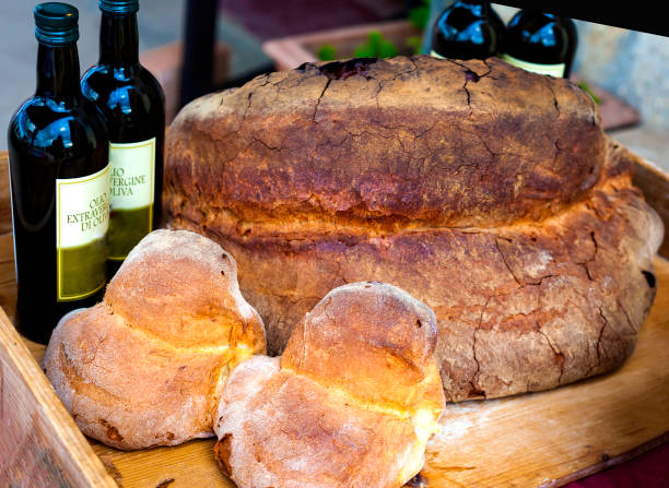 display of matera bread of different sizes, bottles with the indication of "extra-virgin olive oil".
the bread has a crunchy brown crust and a straw-yellow internal crumb with a wonderful soft honeycomb - virgin olive oil imagens e fotografias de stock