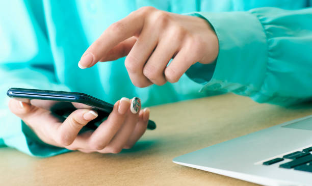 istock Young woman using smartphone for surfing and browsing Internet, searching for required information, sitting at desk with laptop. 1147371780