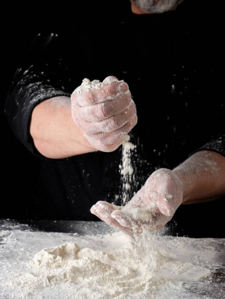 istock chef in black uniform sifts through his fingers white wheat flour 1147373869