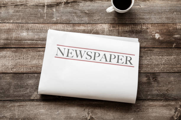 istock Newspaper and coffee on wooden background 1147375371