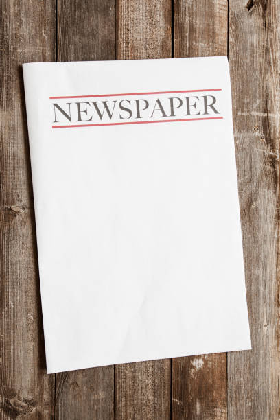 Fresh news in daily papers, tied with rope and rubber seal. Two rolled newspapers on wooden table, side view
